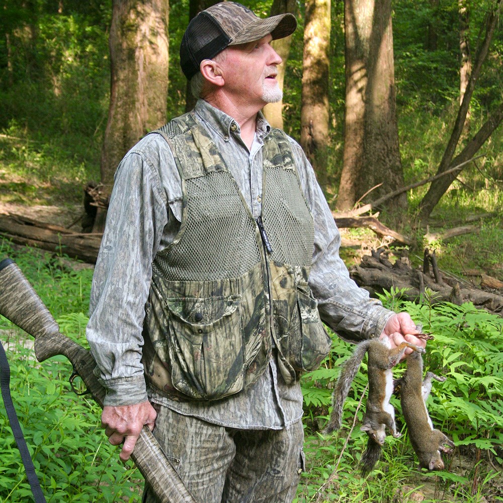 Male hunter holding two squirrels.