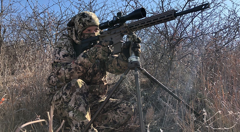 Hunter in camouflage shooting modern sporting rifle.