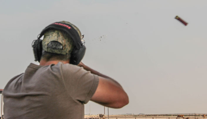 Rear view of a man shooting birds in a field