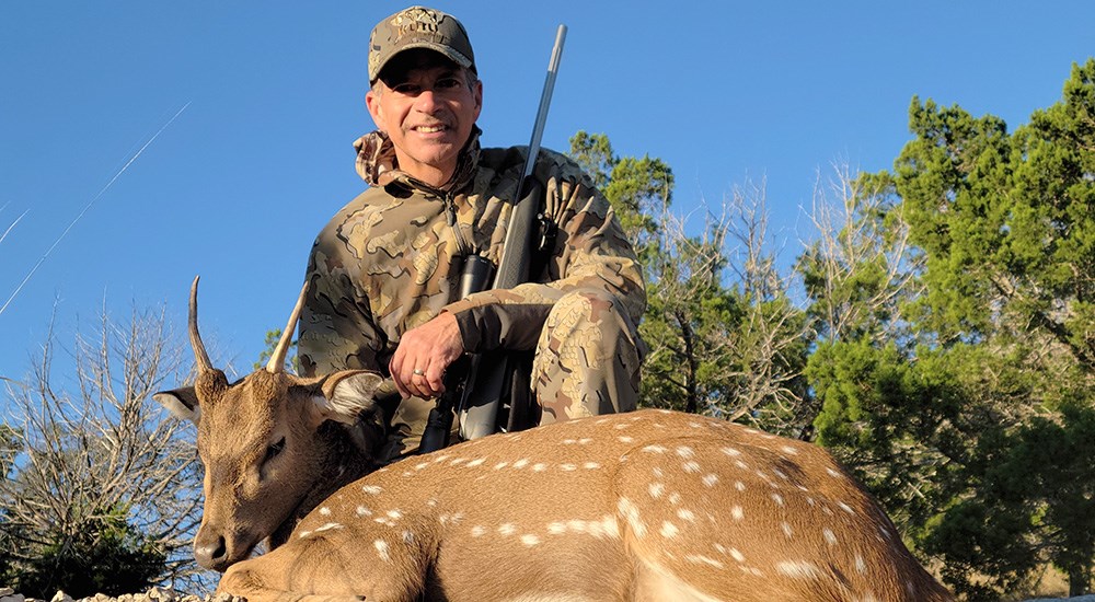 Hunter posing with axis deer harvested in Texas.