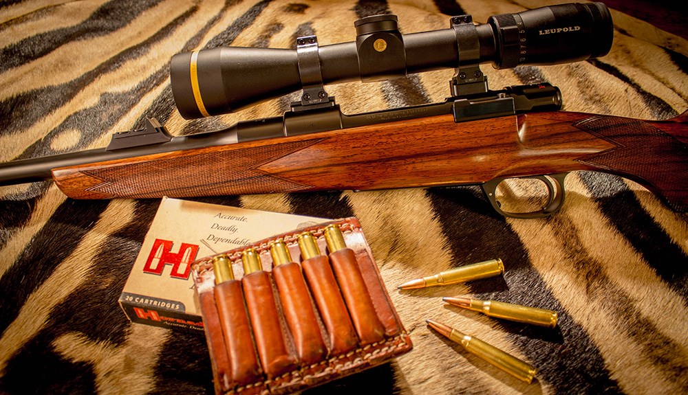 Rigby Highland Stalker rifle with Leupold rifle scope and Hornady .275 Rigby ammunition atop a zebra rug.