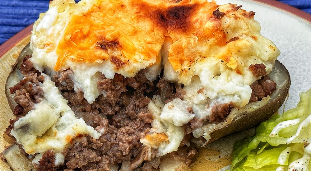Venison stuffed baked potato with melted cheddar cheese sprinkled on top.