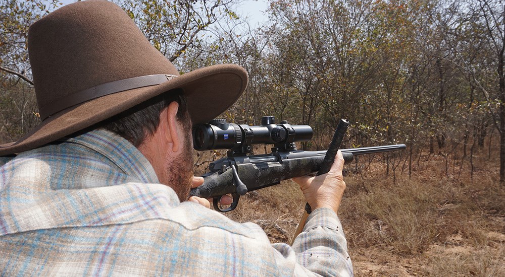 Hunter shooting rifle off shooting sticks