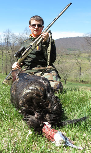 Young hunter with shotgun mounted with TruGlo Gobbler-Stopper, with slain turkey in front of him.
