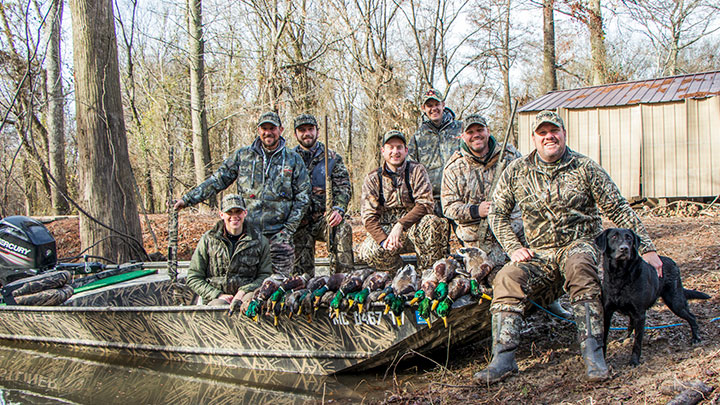 Waterfowl hunters with mallard ducks and black Labrador Retriever