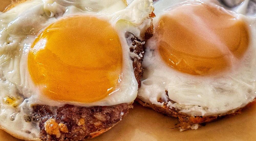 Venison sausage on biscuit with fried egg on top.