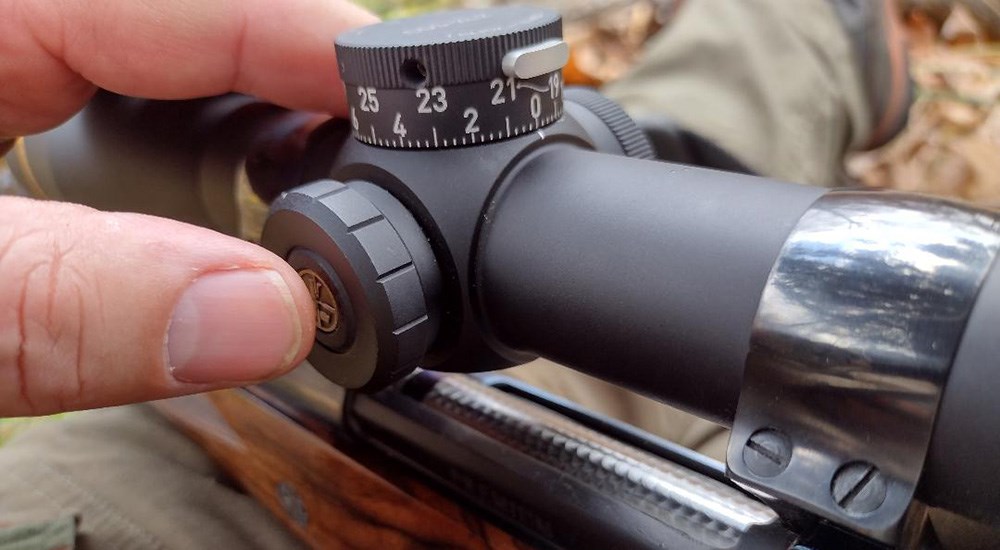 Finger depressed on illumination reticle button on Leupold riflescope.