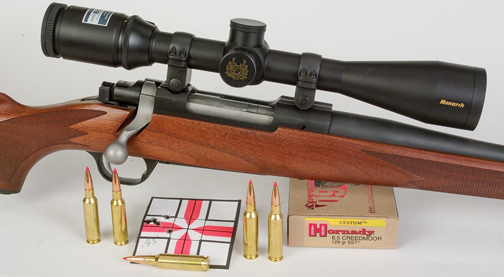 Bolt action rifle with rifle target and Hornady 6.5 Creedmoor hunting ammunition.