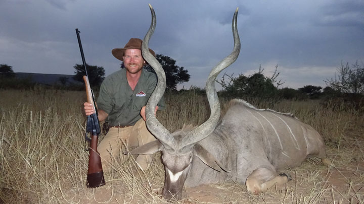 Hunter poses with kudu against a graying sky