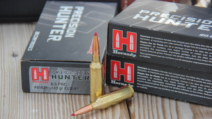 Three boxes of Hornady 6.5 PRC behind two 6.5 PRC Cartridges