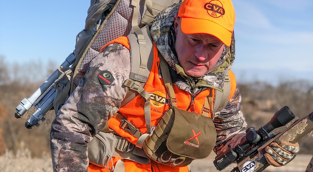 Male hunter in camouflage and orange vest and hat.