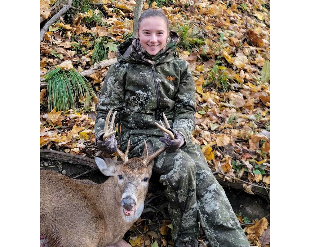 Young female hunter with whitetail buck in Indiana