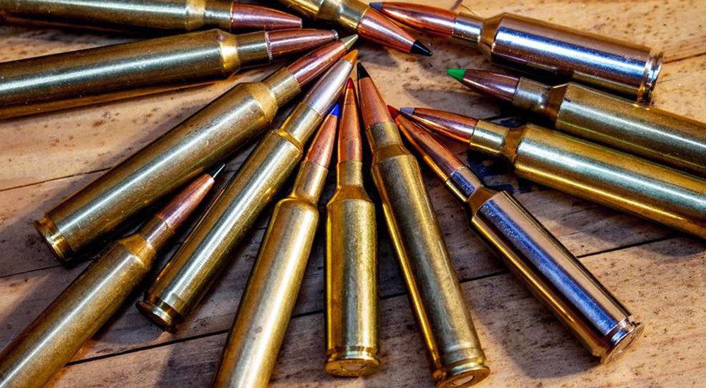 Several rounds of rifle ammunition cartridges on wooden table.