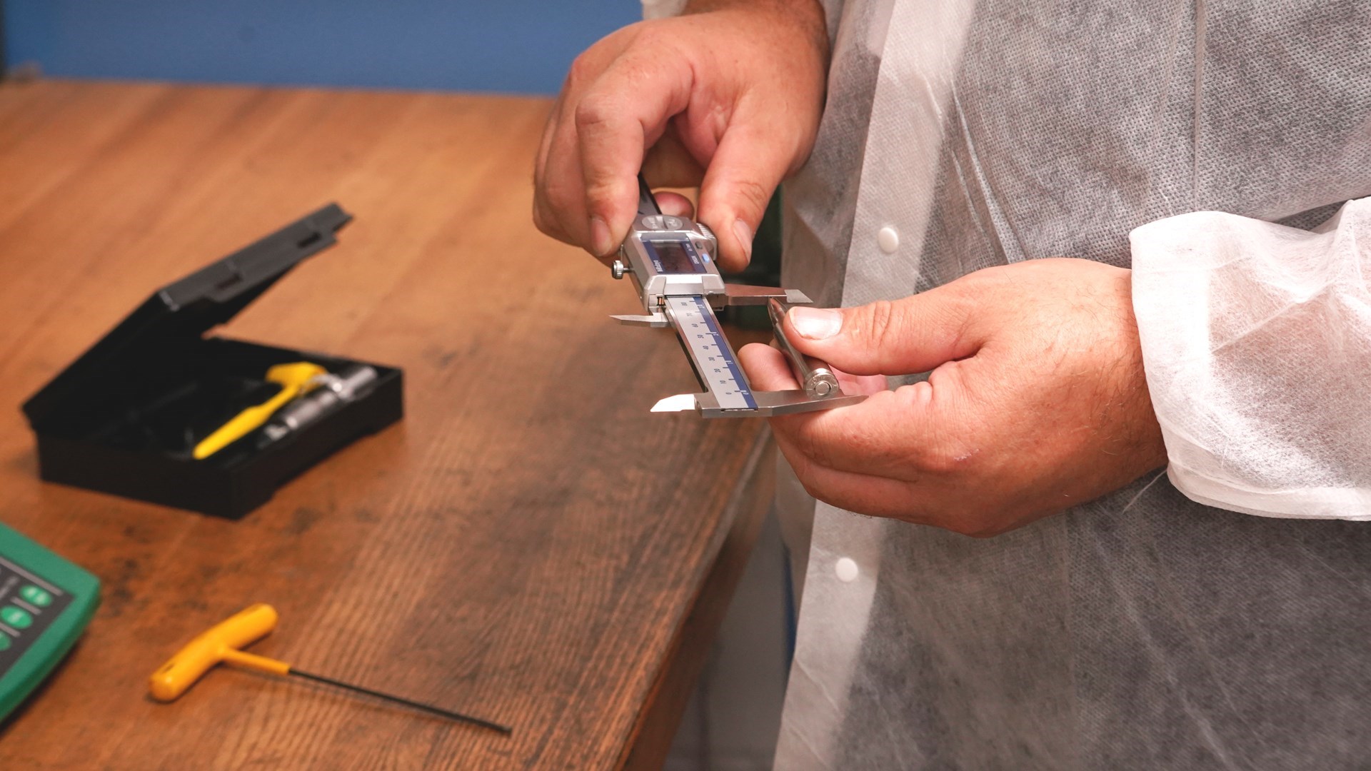 Reloading ammunition 7mm Backcountry man hands using gauge micrometer to measure silver steel case overall length