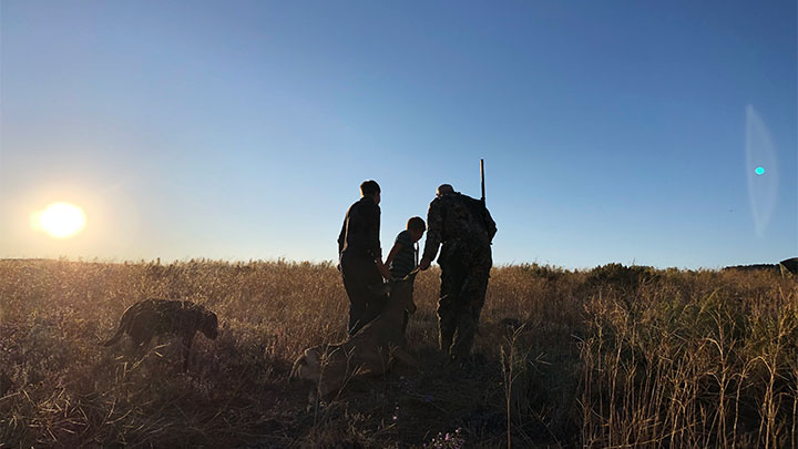 Hunters Dragging Deer in Field