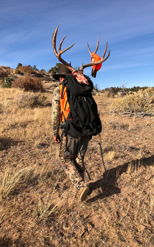 Hunter with antlers walking across a field