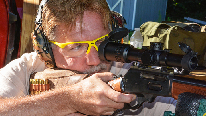 Man Shooting Lever-Action Rifle off Shooting Bench