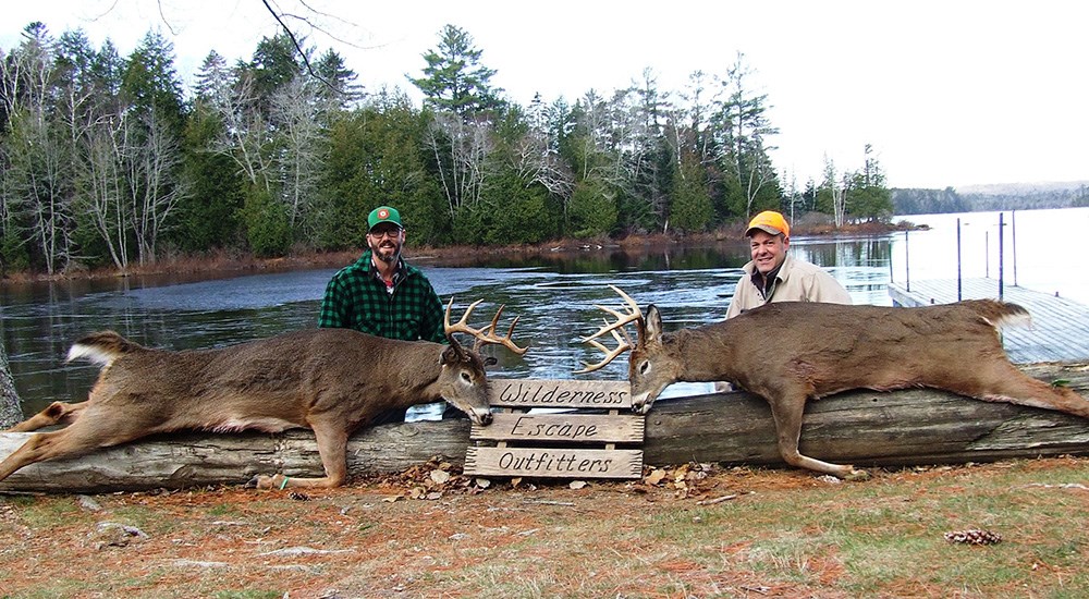 Two hunters posing with large whitetail bucks at Wilderness Escape Outfitters in Maine.