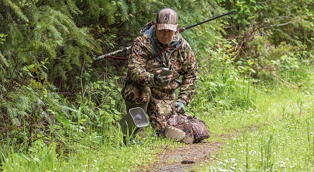 Hunter using electronic caller in green forrest.