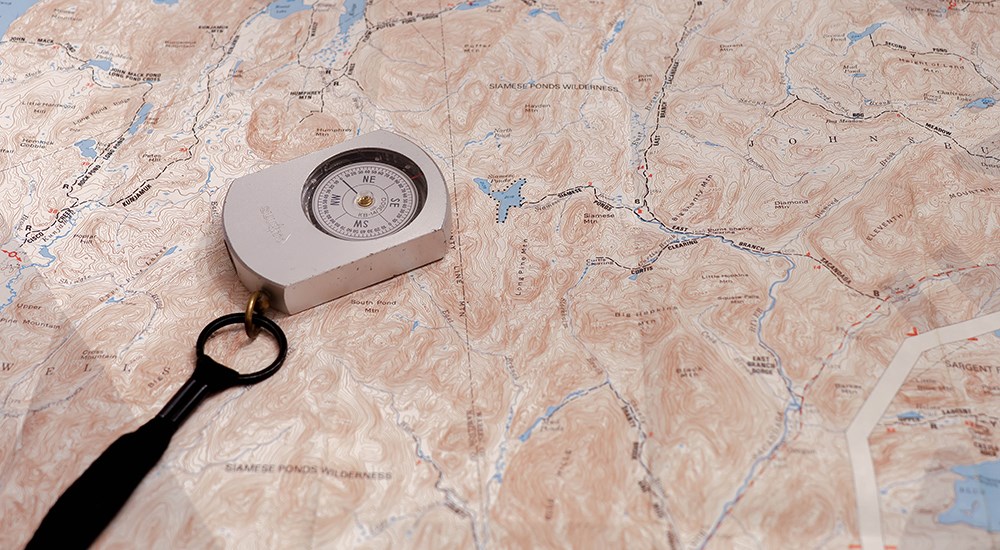 Map with compass laying on top.