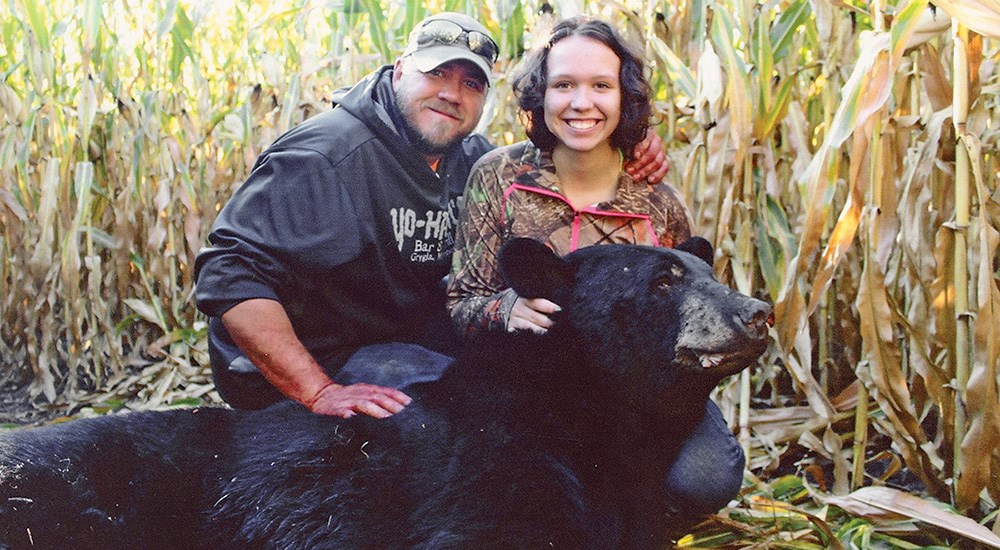 Youth female hunter with male father and large black bear.