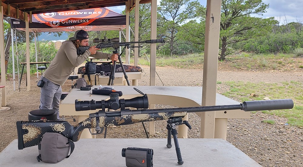 Adult male shooting rifle off of tripod on shooting range.