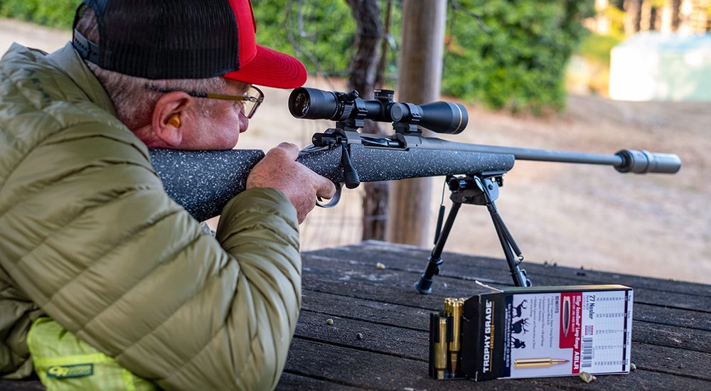 Male shooting Nosler Model 21 rifle from shooting bench.