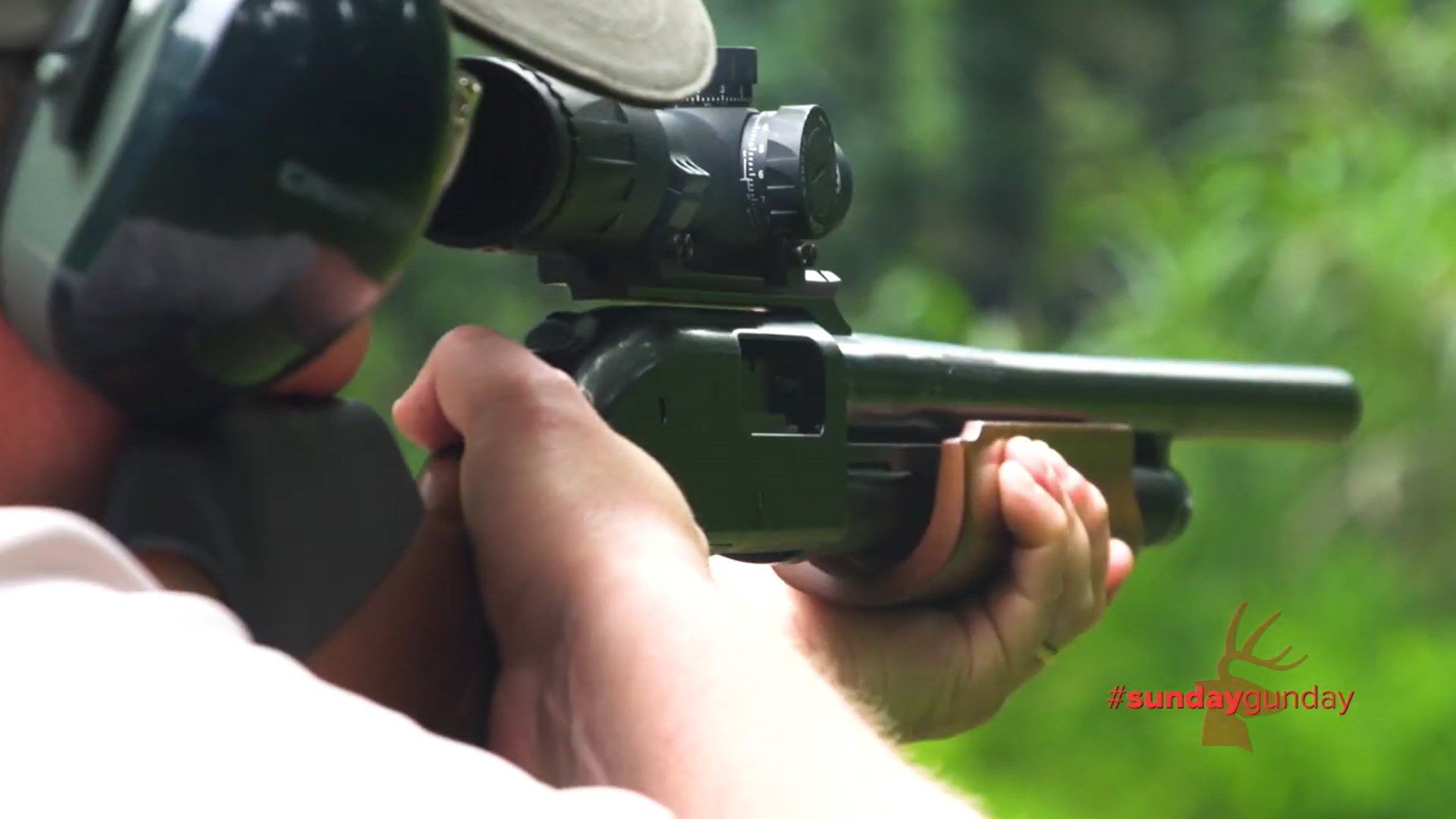 Mossberg 500 Combo Field/Deer pump-action shotgun outdoors rear view in shoulder being fired by an wearing earmuffs and ballcap looking through riflescope on slug barrel