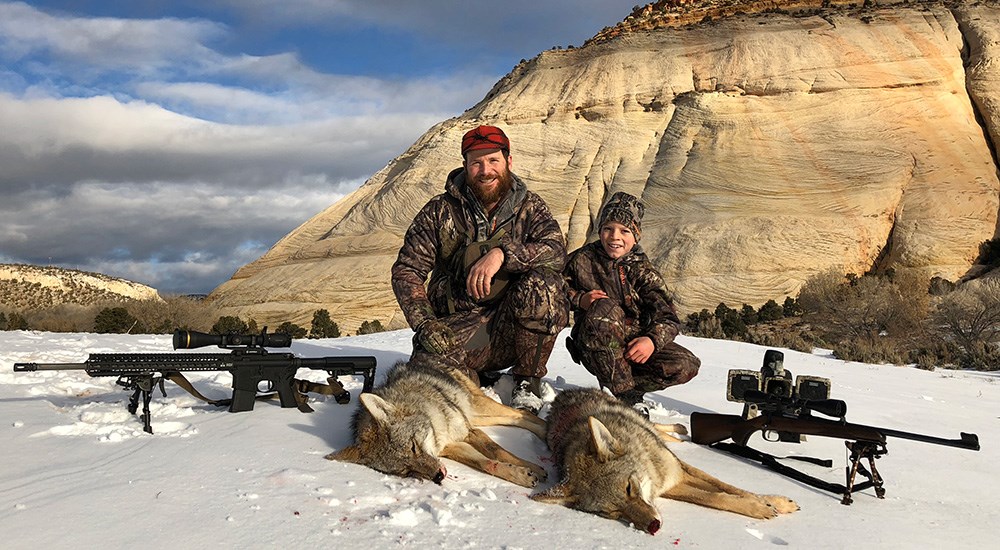 Adult male with young son hunting coyotes in Utah mountains.