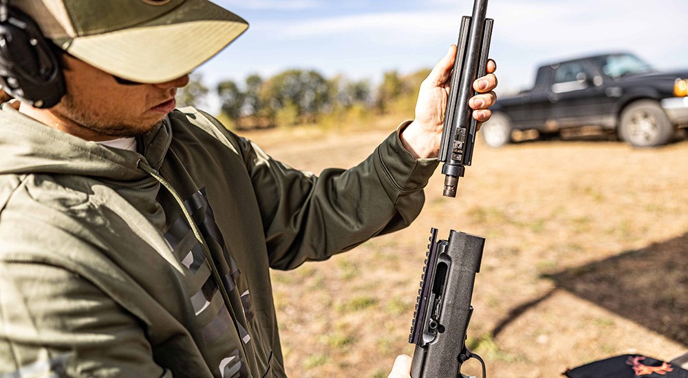 Male removing the barrel from Savage A22 Takedown rimfire rifle.