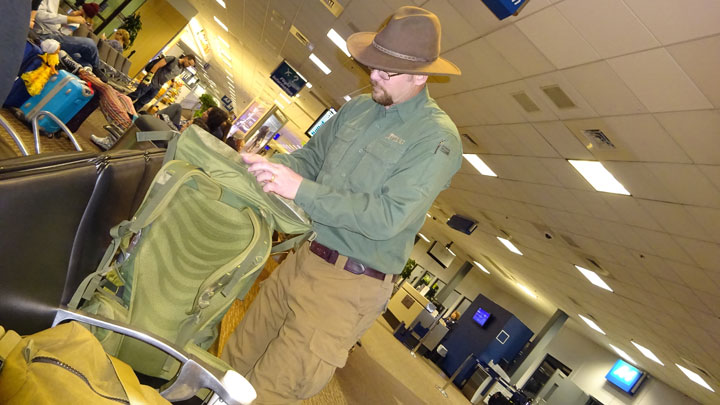 Author Aram von Benedikt dons his pack in the airport, getting ready to board his plane