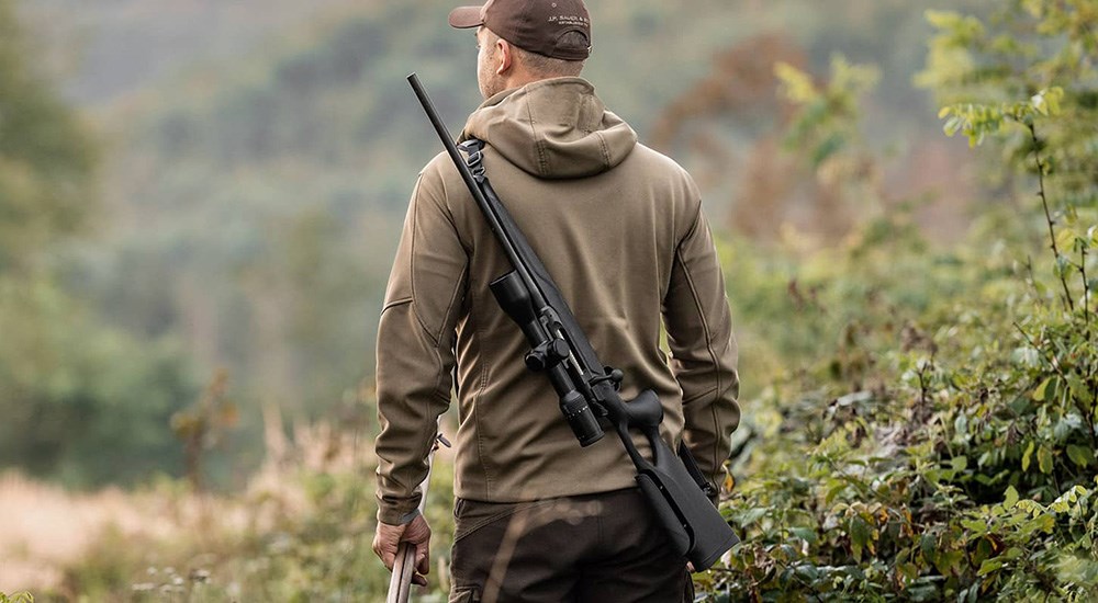 Male hunter carrying Sauer 505 bolt action rifle.