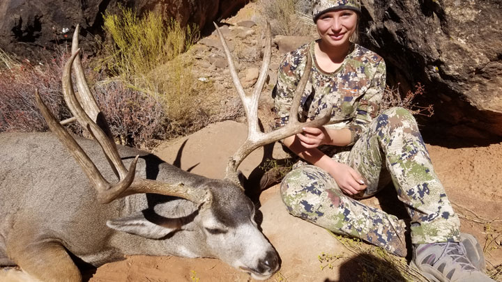 Huntress holding mule deer by the antler