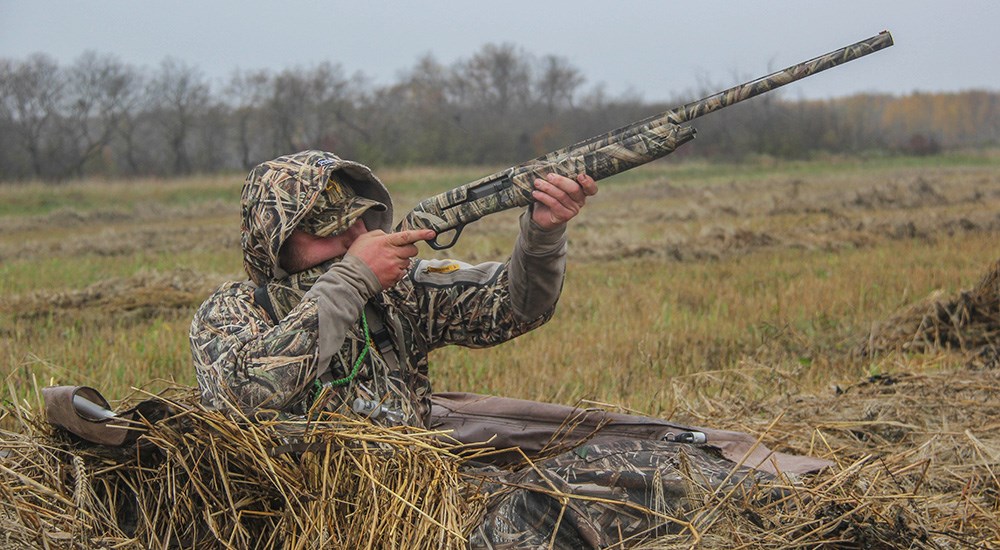 Hunter shooting shotgun while waterfowl hunting.