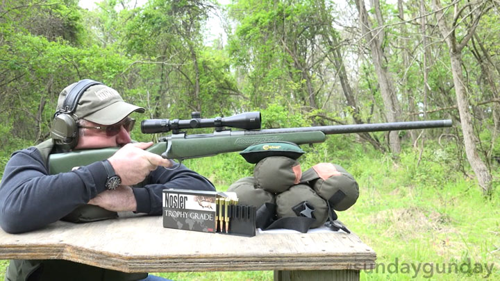 Scott shooting the Nosler M27 with a box of ammunition next to him