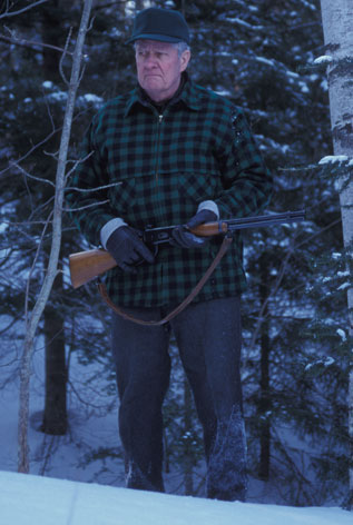 John Kascenska tracking whitetails through the snowy woods with a lever-action .30-30 in hand.