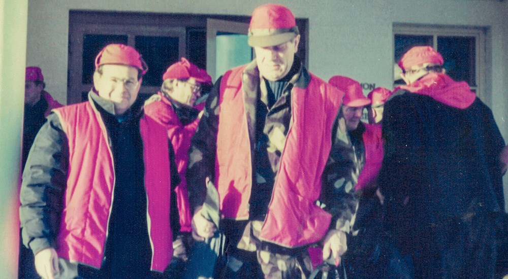 Male hunters wearing orange vests in Finland.