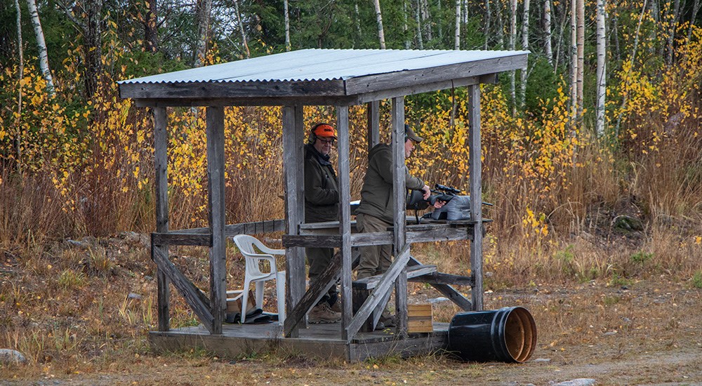 Two males shooting rifle from shooting stand in Finland.