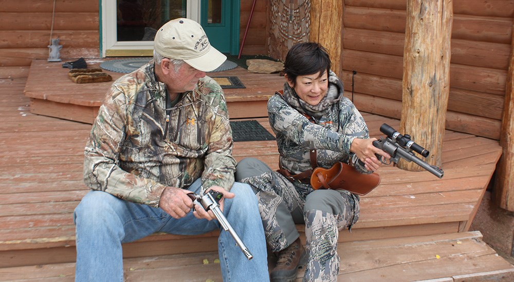 Male and female hunters holding handguns while elk hunting.