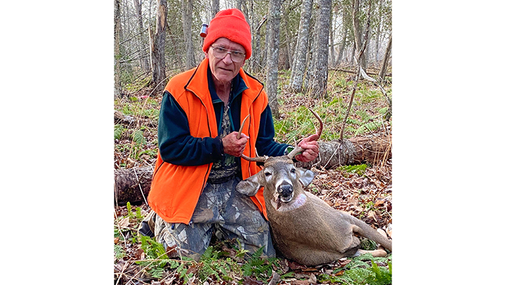 Elderly hunter with whitetail buck in Maine