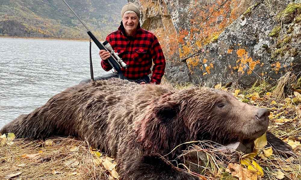 Male hunter with large brown bear in Alaska