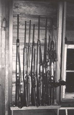 Black and white photograph of a gun rack with .30-06 Springfield-chambered rifles on it.