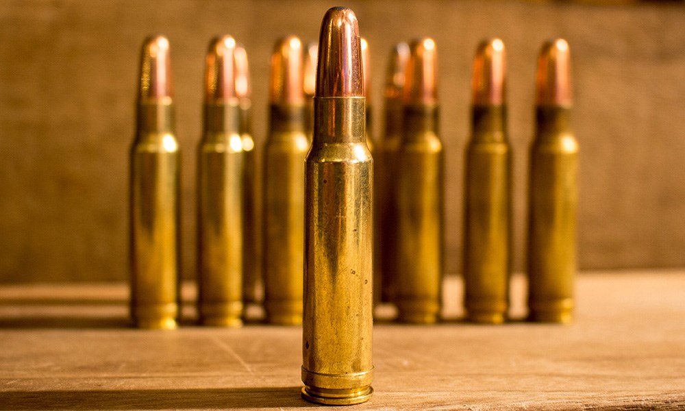 350 Remington Magnum single cartridge standing on wooden table.