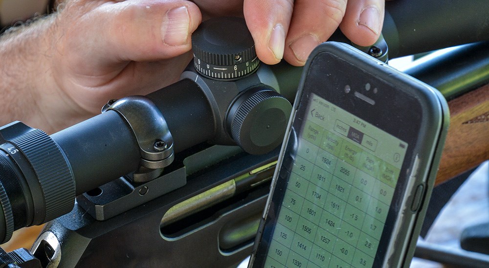 Male using ballistic bullet app to zero rifle scope to maximum point blank range.