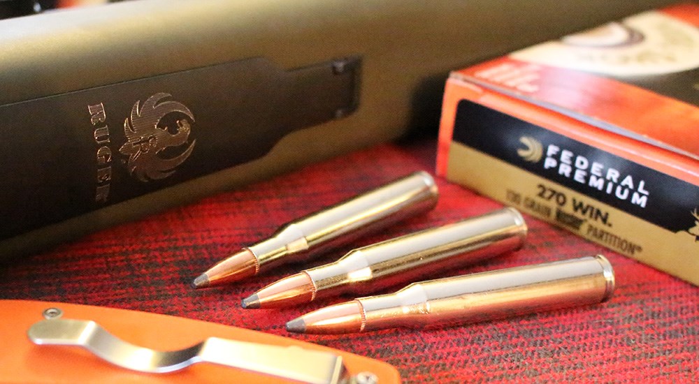 Federal Premium .270 Winchester ammunition laying next to Ruger rifle.