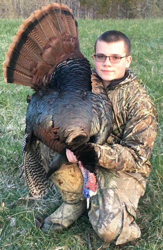 Young hunter poses with dead turkey.
