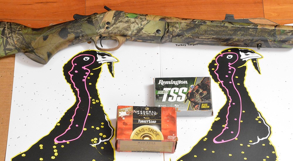 Henry Single Shot Turkey shotgun laying on table with two turkey targets showing pellets.