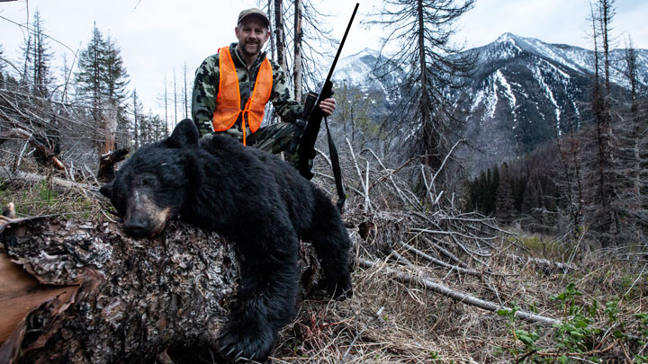Hunter standing behind a downed black bear.