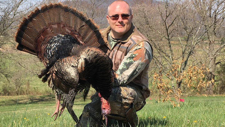 Proud hunter holding a large turkey, fan fully spread