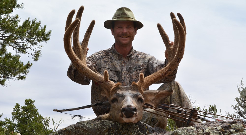 Male hunter posting with whitetail deer in velvet.